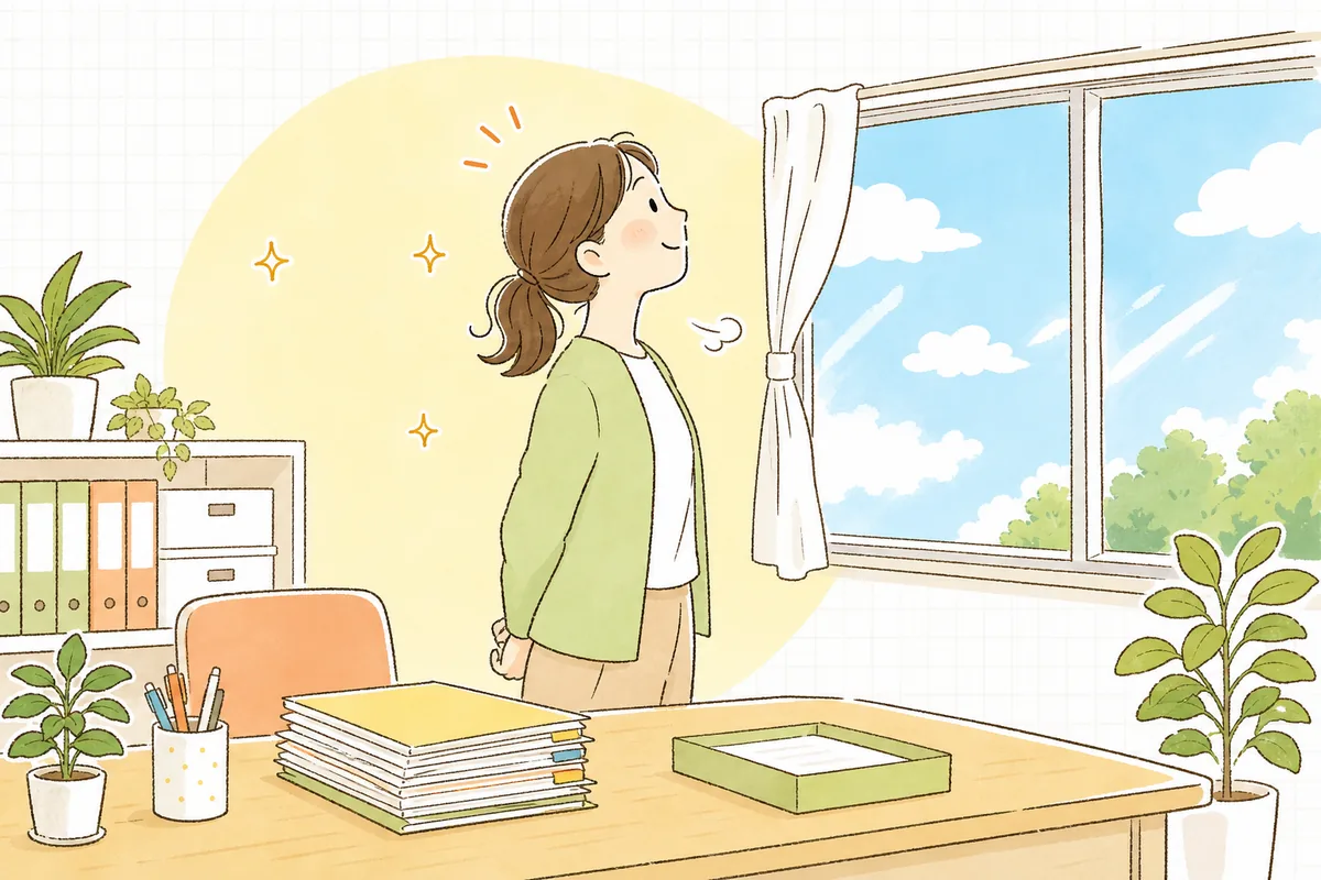 見直しを終えて片づいたデスクのそばで、窓の外の明るい空を見上げてほっとひと息つく介護事業所の事務担当者